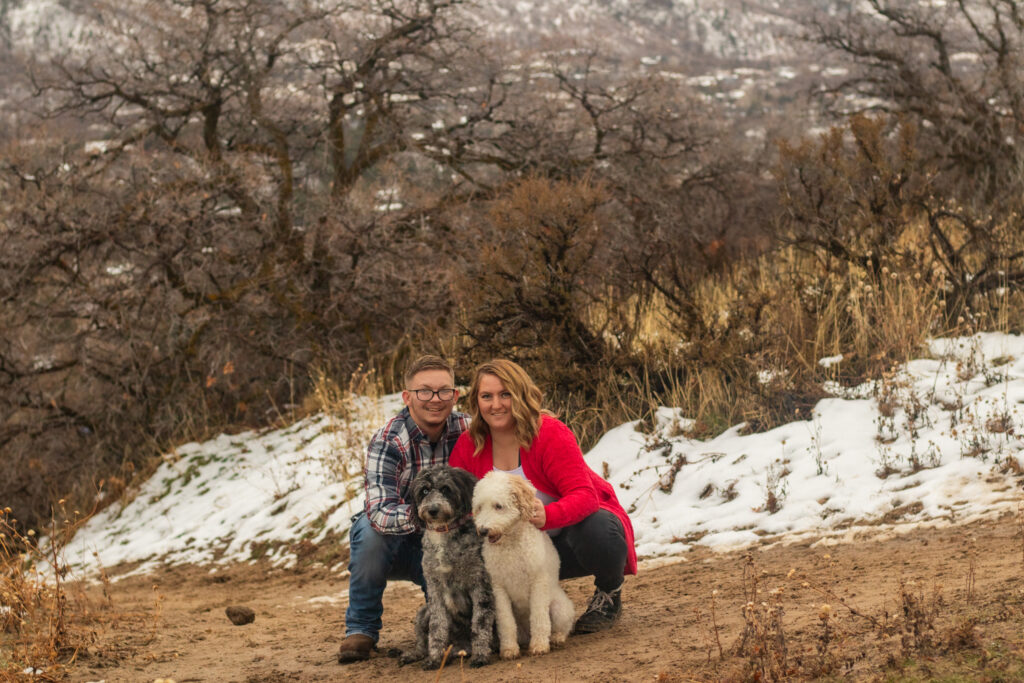 Young couple crouched down next to their 2 dogs at Dimple Dell Park